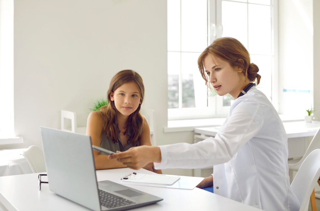 Female doctor speaking with a teenage girl during a medical consultation