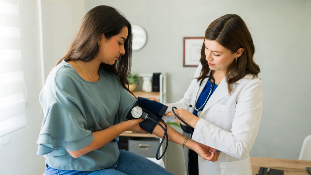 Female doctor checking a young woman’s blood pressure during a routine health exam
